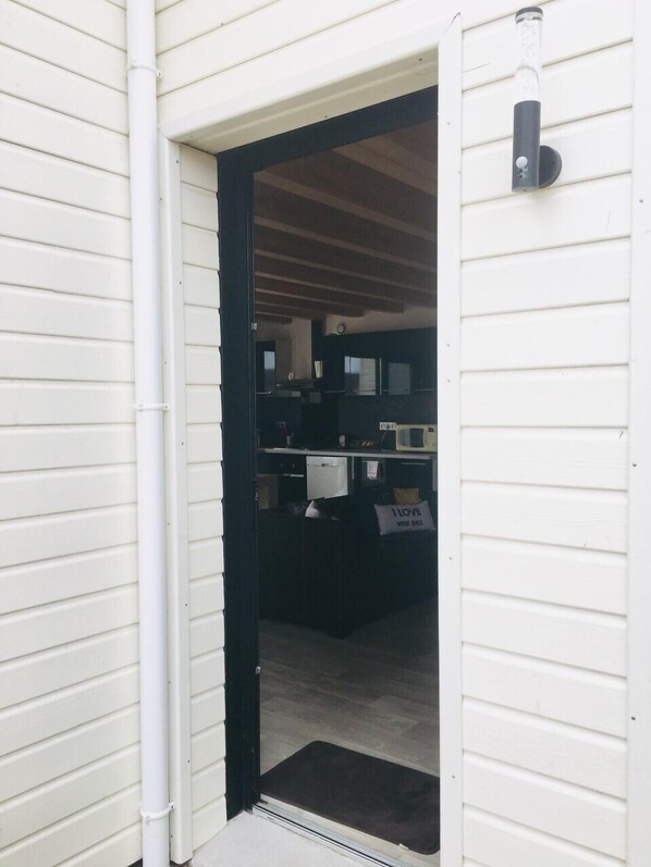 A doorway leading into a room with a black door frame, a white exterior wall, and a small black mat at the entrance. - Cosy cottage with direct access / 800m from the sea. (Quiberon)