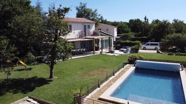 Una casa con piscina, patio cubierto y jardín.