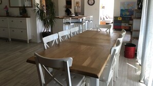 A spacious dining area with a wooden table and white chairs, a kitchen in the background, and a large mirror on the wall. - Pleasant house in Luberon with swimming pool, France (Viens)