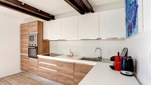 A modern kitchen with wooden cabinets, a built-in microwave, oven, and a stainless steel sink. - T2 Marché de Forville CANNES (Cannes)