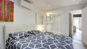 A bedroom with a bed, a bedside table, a mirror, and a bathroom visible through an open door. - T2 Marché de Forville CANNES (Cannes)