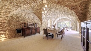 A dining area with a stone archway, a wooden cabinet, and a table set for dining.