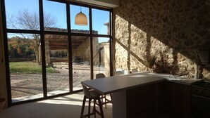 A kitchen with a large window, stone walls, and a view of the outdoors.