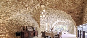 A dining area with a stone archway, a wooden cabinet, and a table set for dining. - 18th century provencal country house in the Luberon Natural Park  (La Tour-d'Aigues)