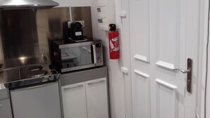 A compact kitchen with a microwave, coffee maker, and a fire extinguisher mounted on the wall. - Mini gîte, studette  (Bonny-sur-Loire)