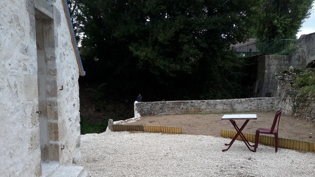 An outdoor patio area with a gravel floor, a table, and a chair. - Mini gîte, studette  (Bonny-sur-Loire)