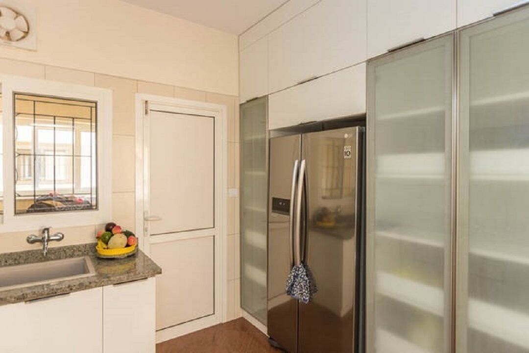 A kitchen with a stainless steel refrigerator, a sink, and a window with a view of the outside.