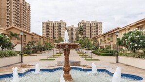 A fountain in a courtyard with high-rise buildings in the background. - Close to Airport and Manyata Tech Park |  25% Off for Long Stays (BENGALURU)