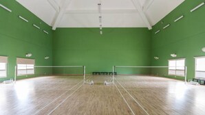 A large indoor sports hall with a wooden floor, green walls, and a high ceiling. - Close to Airport and Manyata Tech Park |  25% Off for Long Stays (BENGALURU)