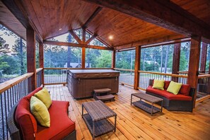 Eine überdachte Terrasse im Freien mit Holzboden, einem Whirlpool und Sitzbereichen.
