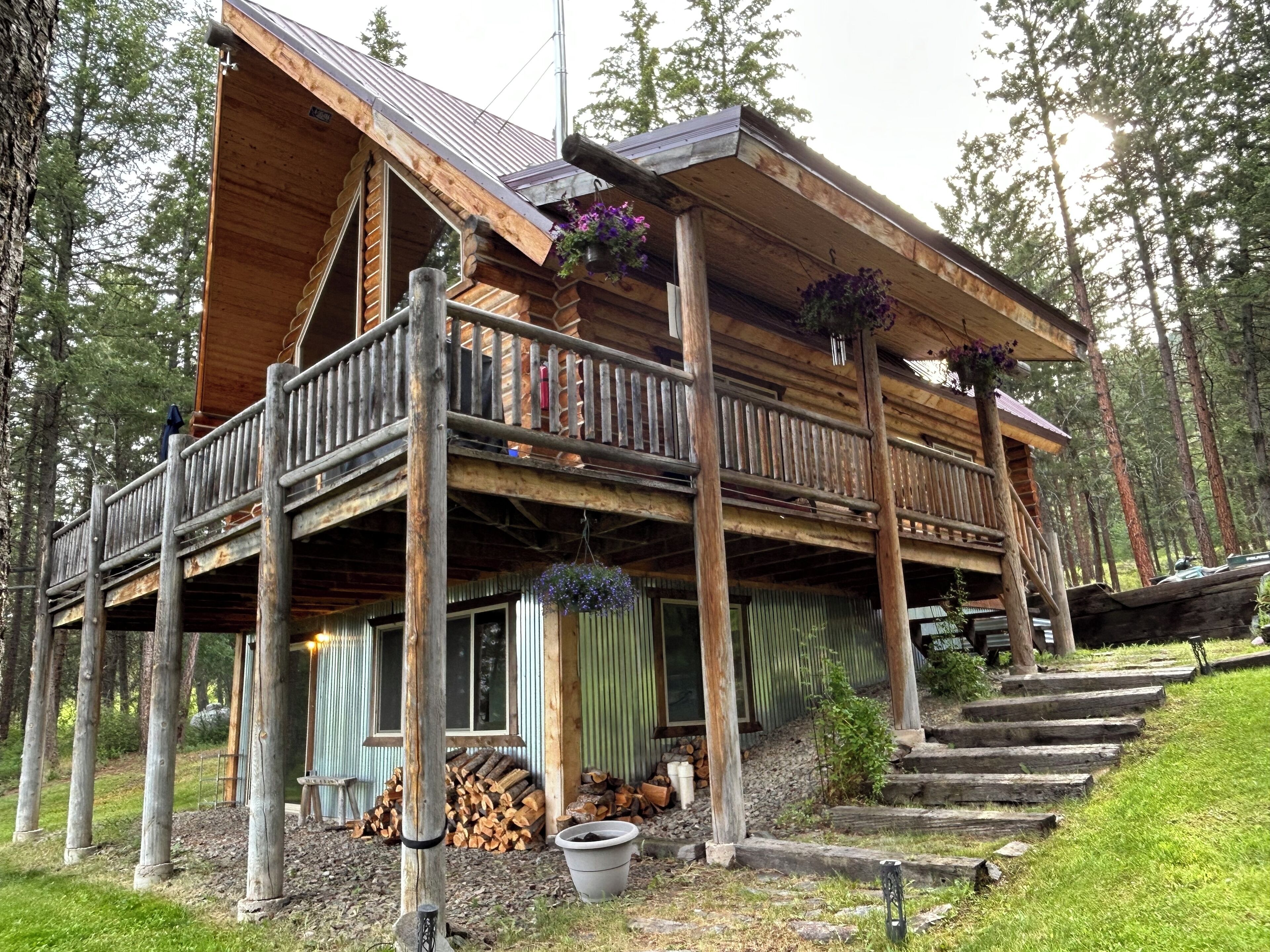 Een vakantiehuis in blokhutstijl met een balkon, houten terras en bloembakken.