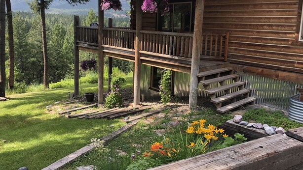 A wooden cabin with a balcony overlooking a forested area.