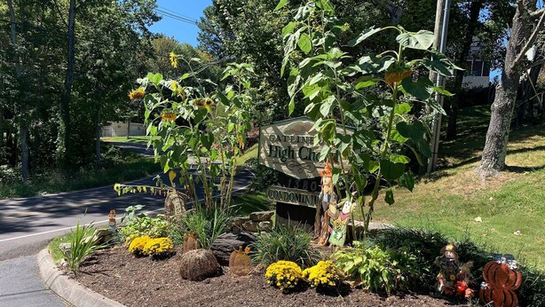 A landscaped garden with a sign for 'High Chas' and a small statue of a scarecrow. - Baby Bear HideAway (Gatlinburg)