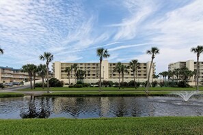 A hotel with multiple floors, a swimming pool, and palm trees. - Unsurpassed Oceanfront Beauty (Crescent Beach)