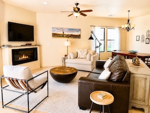 A living room with a fireplace, sofa, coffee table, TV, and a painting on the wall.