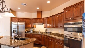 Una cocina moderna con electrodomésticos de acero inoxidable, gabinetes de madera y encimeras de granito, además de un horno empotrado.