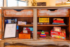 A wooden cabinet with various board games and a framed menu.