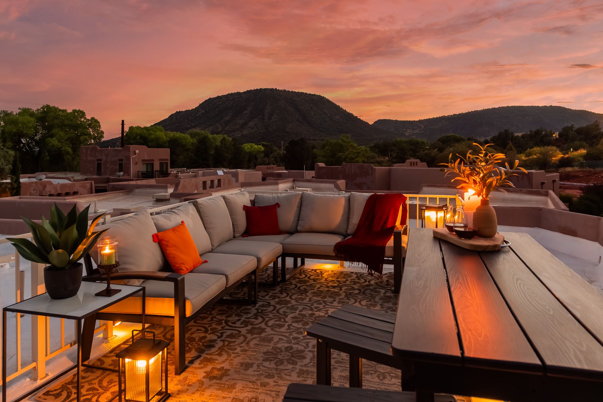 Eine Dachterrasse mit einer Couch, Stühlen, einem Tisch und einem Blumentopf.