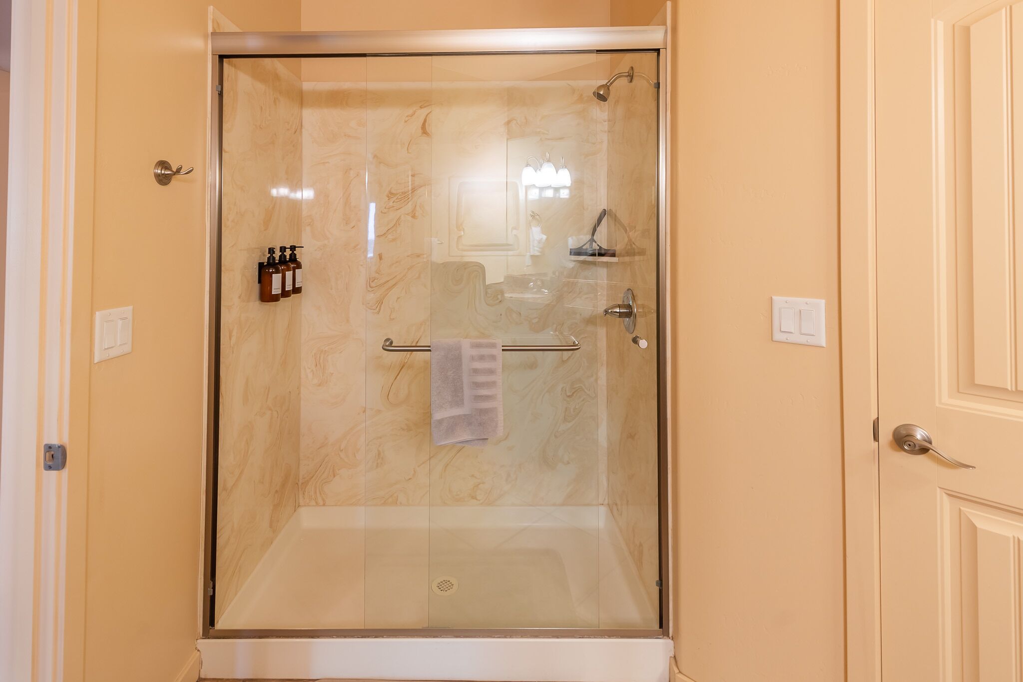 A walk-in shower with a glass door, a towel rack, and a set of toiletries.