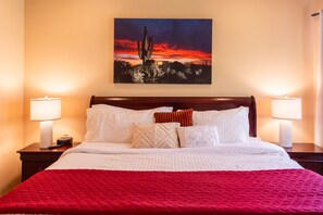 A hotel room with a bed, two bedside lamps, a painting of a desert landscape, and a red throw blanket. - 🌄 Sedona Rooftop Retreat | 360° Views + Walkable (Sedona)