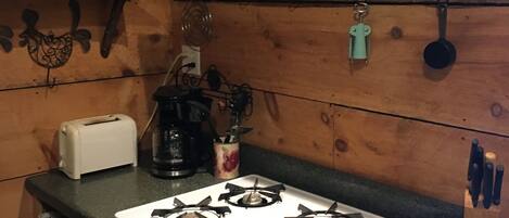 Een keuken met een gasfornuis, een broodrooster en diverse keukengerei.