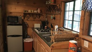 Une cuisine de taille réduite avec des murs en bois, un four à micro-ondes, un réfrigérateur, un évier et une cuisinière.