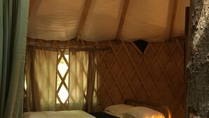 Une tente équipée de deux lits, d’une chaise en bois et d’une table avec une lampe.