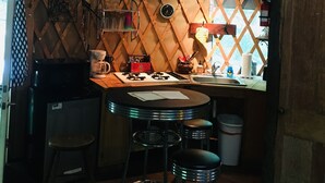 Une cuisine compacte avec un plafond en bois, une cuisinière à gaz, une machine à café et des tabourets de bar.