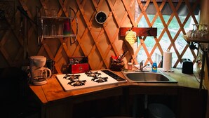 Une cuisine chaleureuse avec un intérieur en bois, une cuisinière à gaz, un évier et divers ustensiles de cuisine.