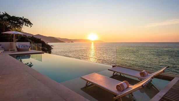 An infinity pool with lounge chairs and a view of the sunset over the sea. - MODERN AND LUXURY OCEANFRONT VILLA (Puerto Vallarta)