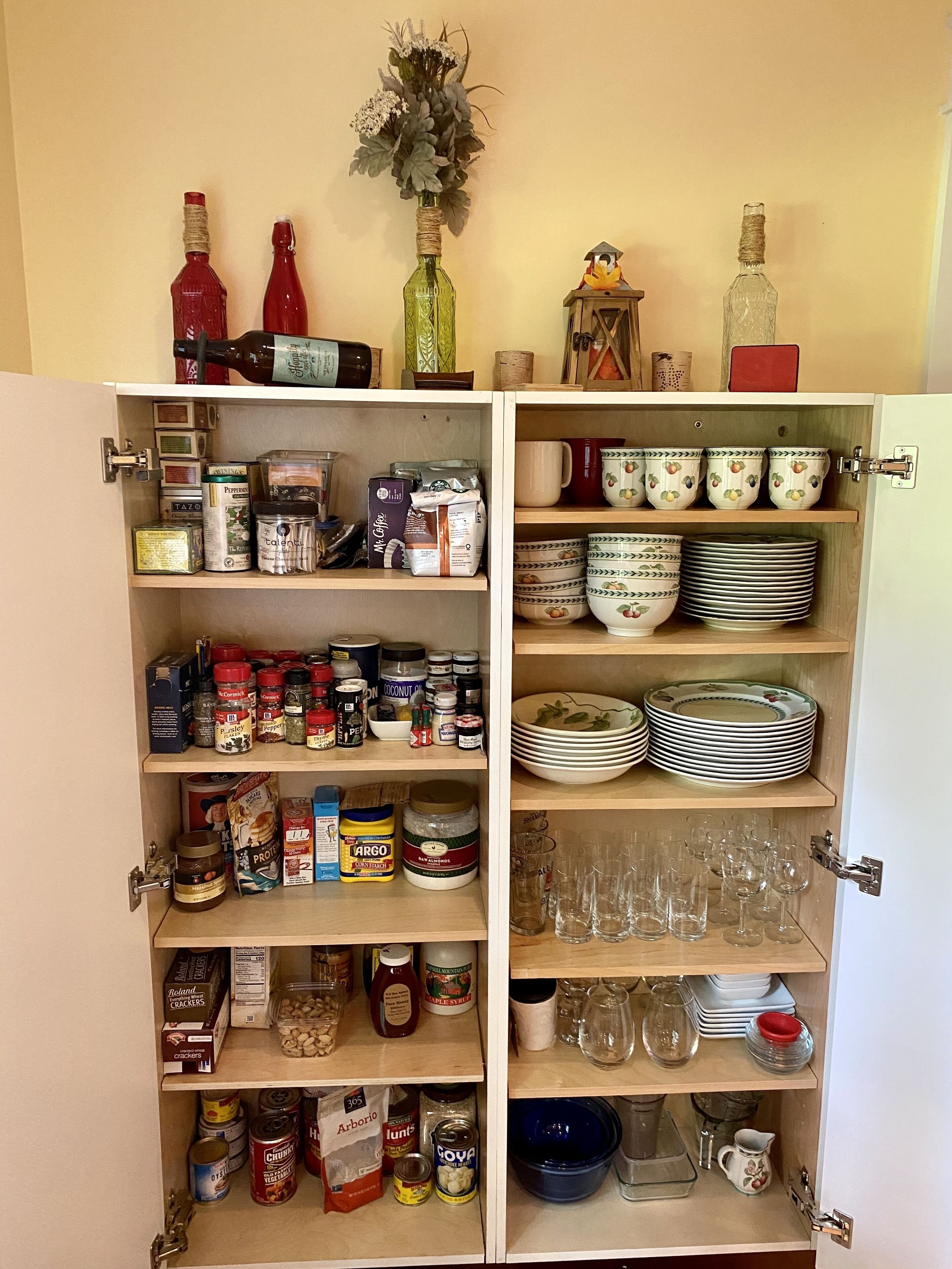 Una despensa con estantes llenos de alimentos, especias y utensilios de cocina.
