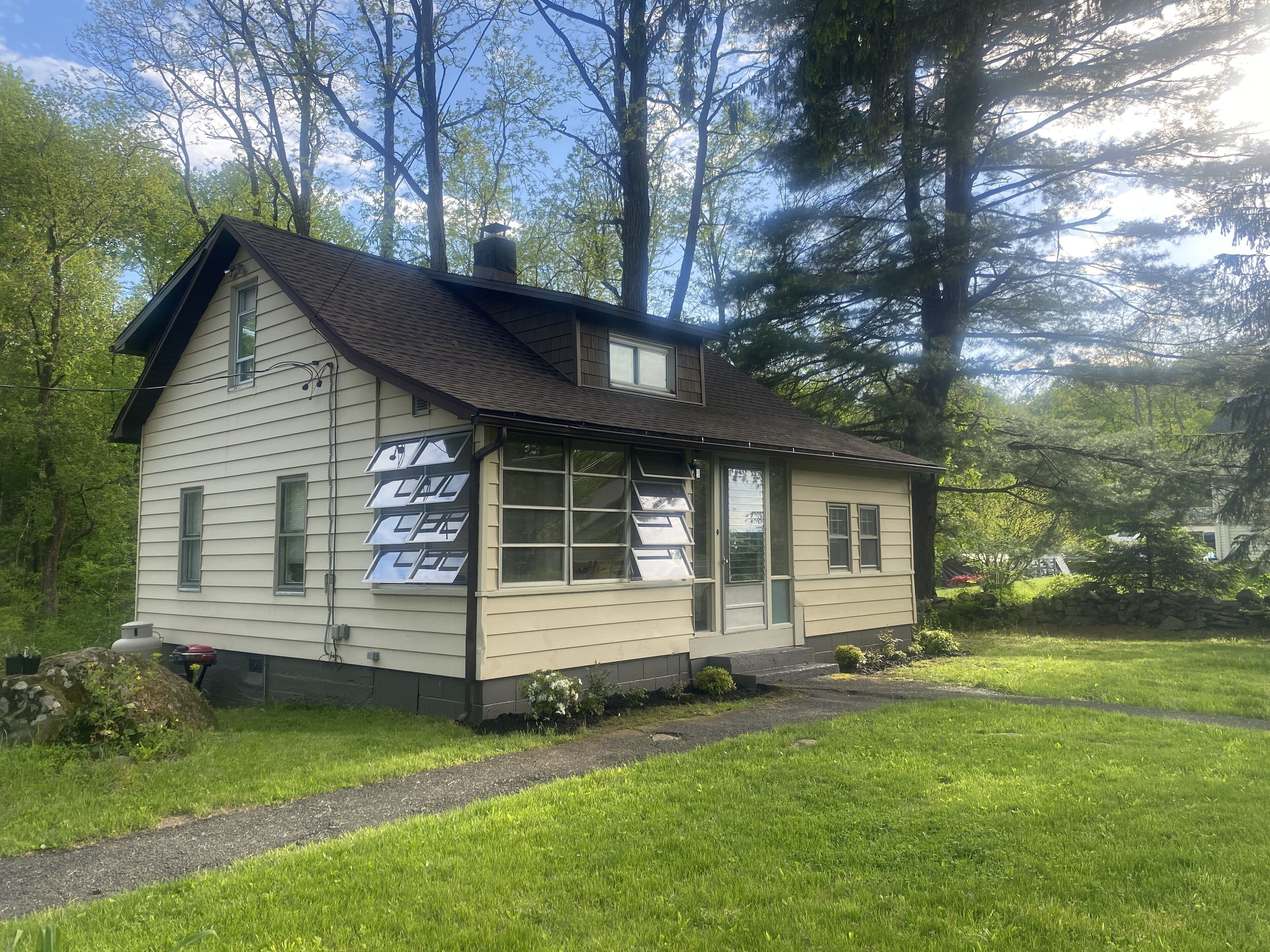 Une petite maison à un seul étage, dotée d’un toit en pente, de grandes fenêtres et d’une cheminée.