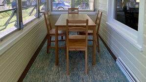 Uma área de refeições com mesa e cadeiras, janelas amplas e vista para o exterior.