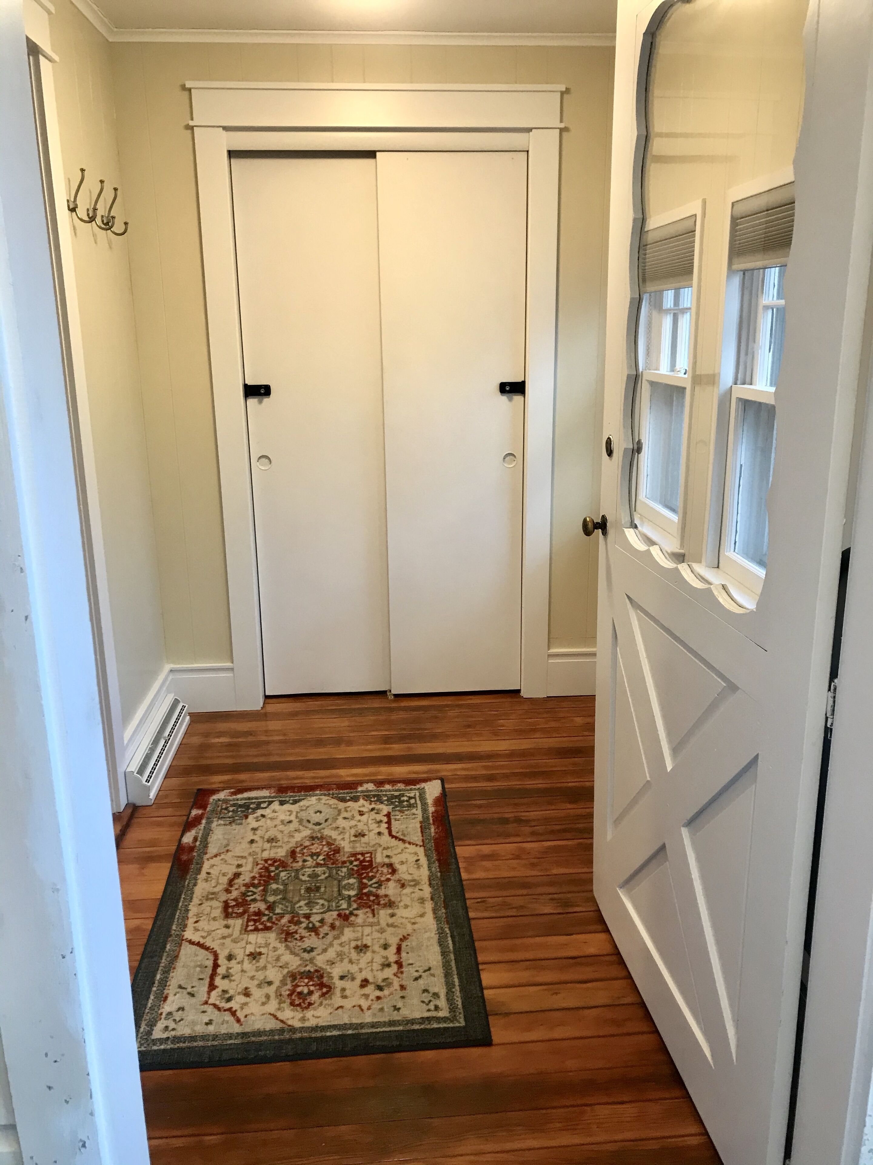 Un couloir avec une porte à deux battants, un tapis à motifs et un radiateur.