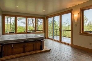 Ein geräumiges Zimmer mit großen Fenstern, einer Whirlwanne und Blick auf eine Terrasse.