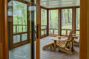 Eine Holterrasse mit großen Fenstern mit Blick auf einen Wald.