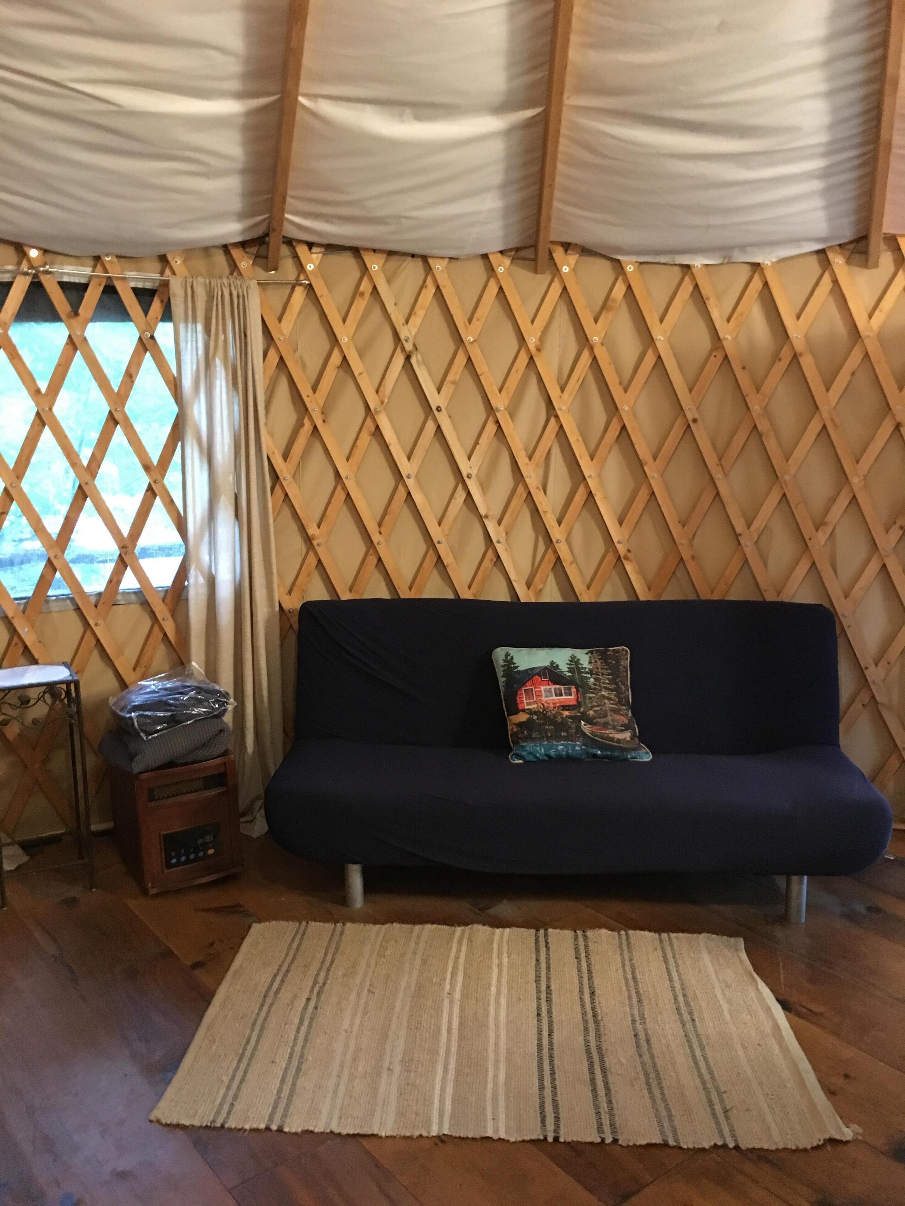 Une pièce avec un canapé bleu foncé, un tapis à motifs, une petite table en bois avec une radio et un mur décoré d’un treillis en bois.