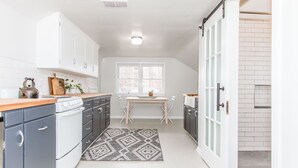 Cozinha moderna com armários brancos, fogão e área de refeições com mesa e cadeiras.