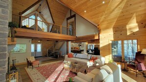Een ruime loft-achtige woonruimte met een hoge plafond, houten balken, een trap en een gezellige zithoek.