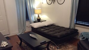 Una sala de estar acogedora con un sofá, una mesita, una lámpara y una rueda de bicicleta decorativa en la pared.