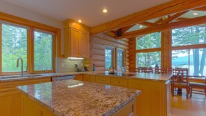 Cucina in stile baita con ampie finestre, mobili in legno e un piano di lavoro in granito.