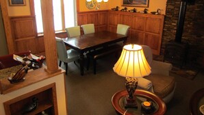 Uma sala de jantar com mesa e cadeiras de madeira, um candelabro e uma lareira de pedra.