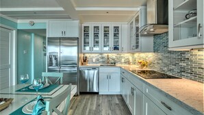 Una cocina moderna con armarios blancos, un refrigerador de acero inoxidable y un salpicadero de azulejos.