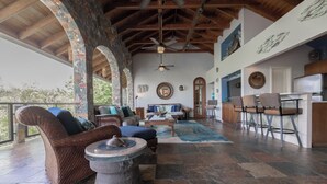 A spacious living area with a stone floor, a wooden ceiling, and a seating area with a sofa and chairs. - Updated Caribbean retreat, with solar and generator power backup (Cruz Bay)
