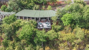 A traditional-style building with a curved roof, surrounded by dense greenery. - Updated Caribbean retreat, with solar and generator power backup (Cruz Bay)