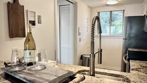 A kitchen with granite countertops, a wine bottle, and glasses on a wooden board. - Eternal Summer 2-bedroom villa steps to Coligny Beach and Plaza (Hilton Head Island)