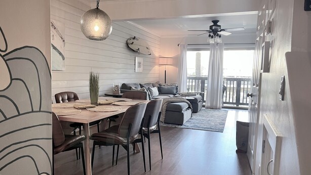 A modern dining area with a wooden table, chairs, and a hanging light fixture. - Eternal Summer 2-bedroom villa steps to Coligny Beach and Plaza (Hilton Head Island)