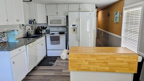 A compact kitchen with white cabinets, a microwave, an oven, and a refrigerator. - Home on canal near Rogers Park, 2 docks, water access to the Gulf, sleeps 10 (Weeki Wachee)