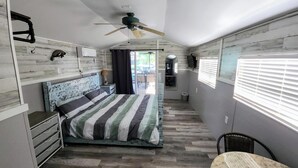 A bedroom with a bed, a ceiling fan, a TV, and a window with blinds. - Home on canal near Rogers Park, 2 docks, water access to the Gulf, sleeps 10 (Weeki Wachee)