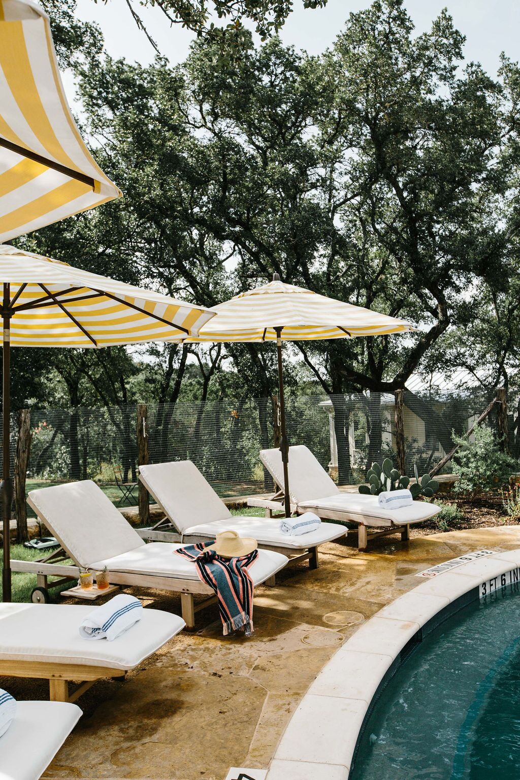 A poolside area with lounge chairs and striped umbrellas.